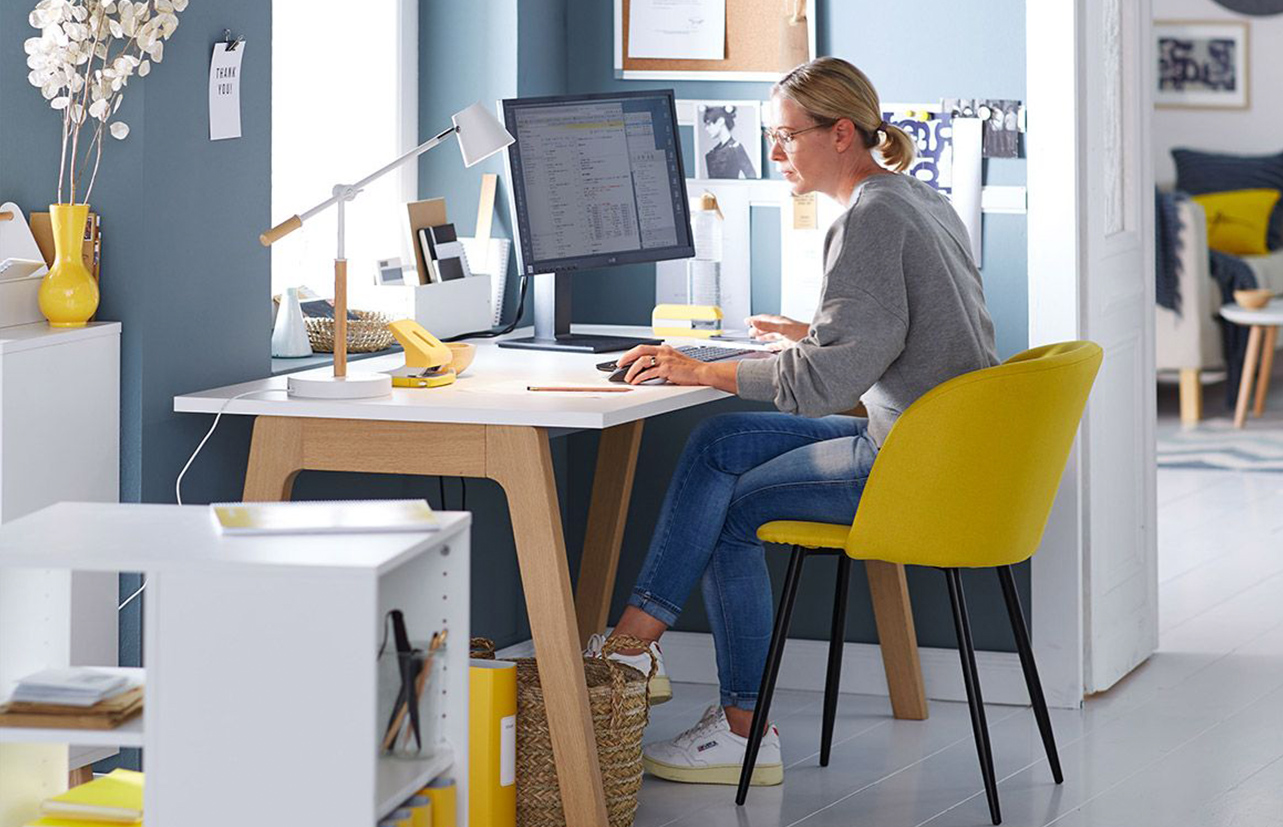 Woman in home office with desk and yellow chair across